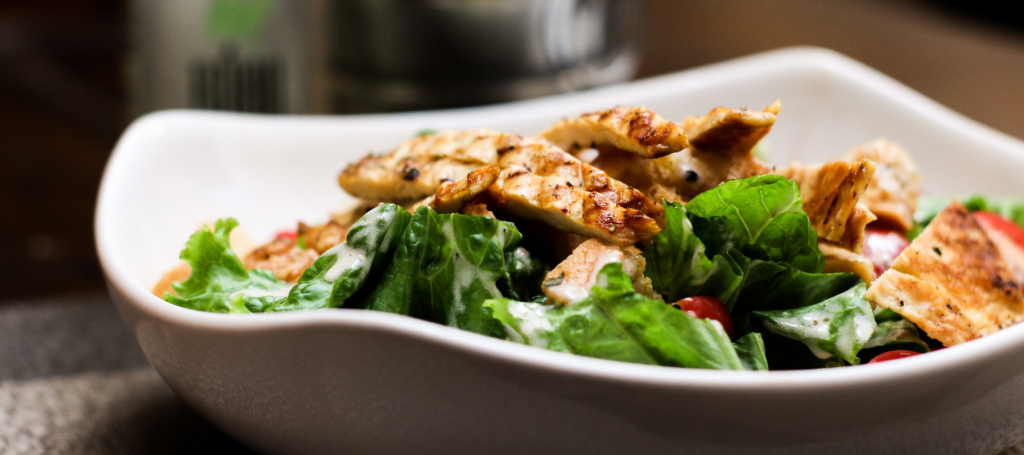 a white bowl of a grilled chicken salad