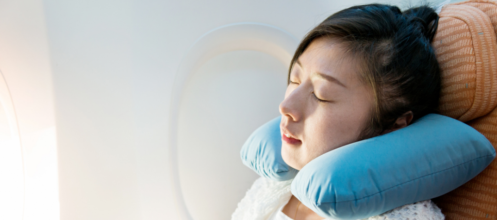 woman wearing neck pillow on airplane